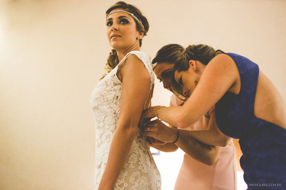 Madrinhas ajudando a noiva a abotoar o vestido