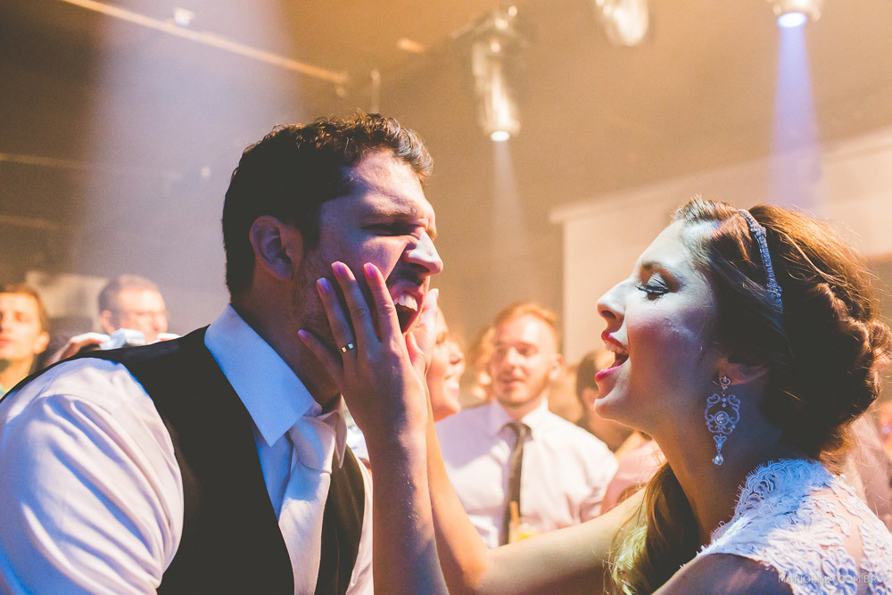 Noiva apertando a bochecha do noivo em festa de casamento na Traffô Eventos