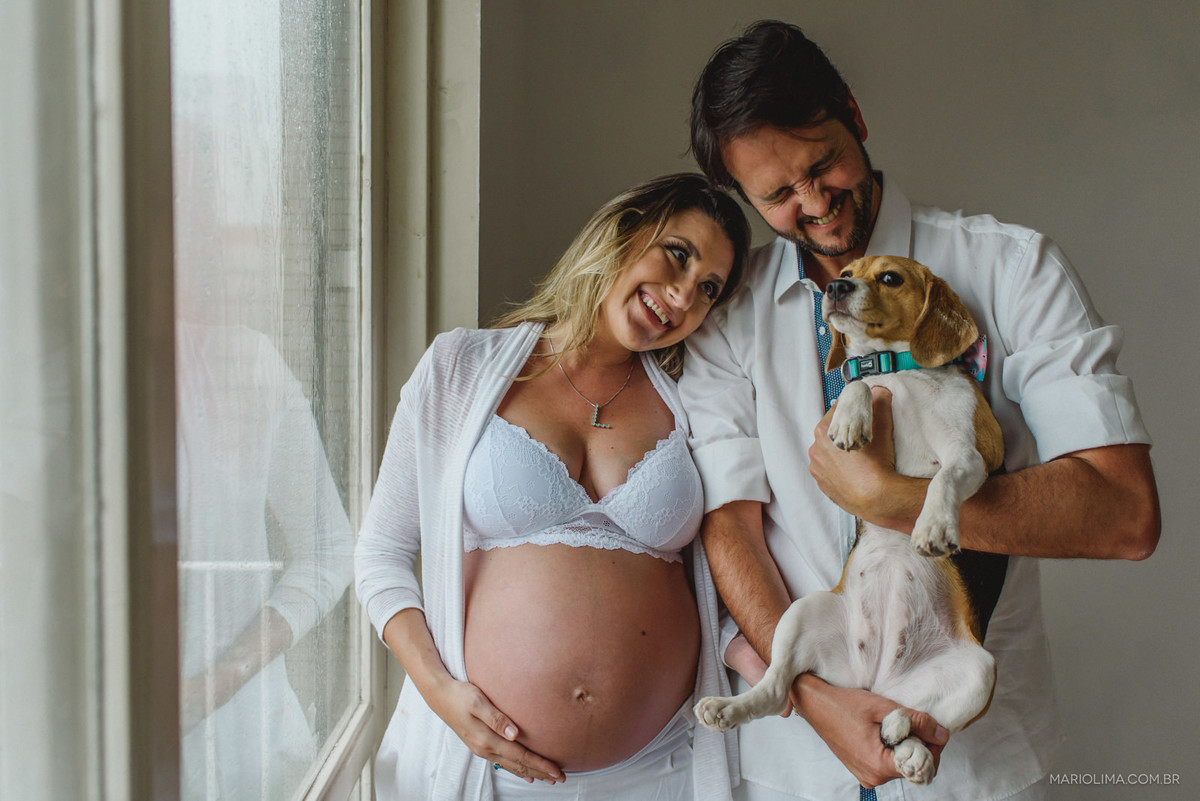 mulher gravida com marido segurando um cachorro da raça beagle