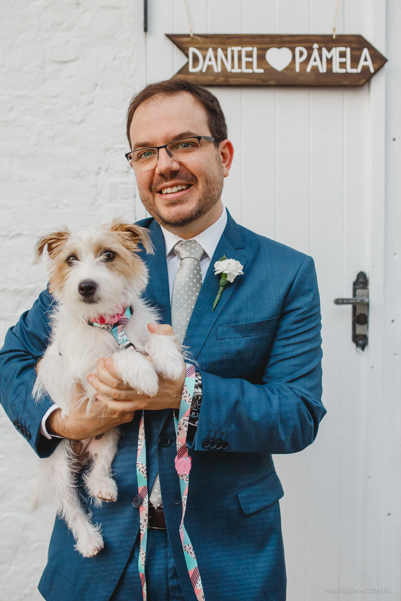 retrato do noivo com terno brooksfield e cachorro jack russell no colo