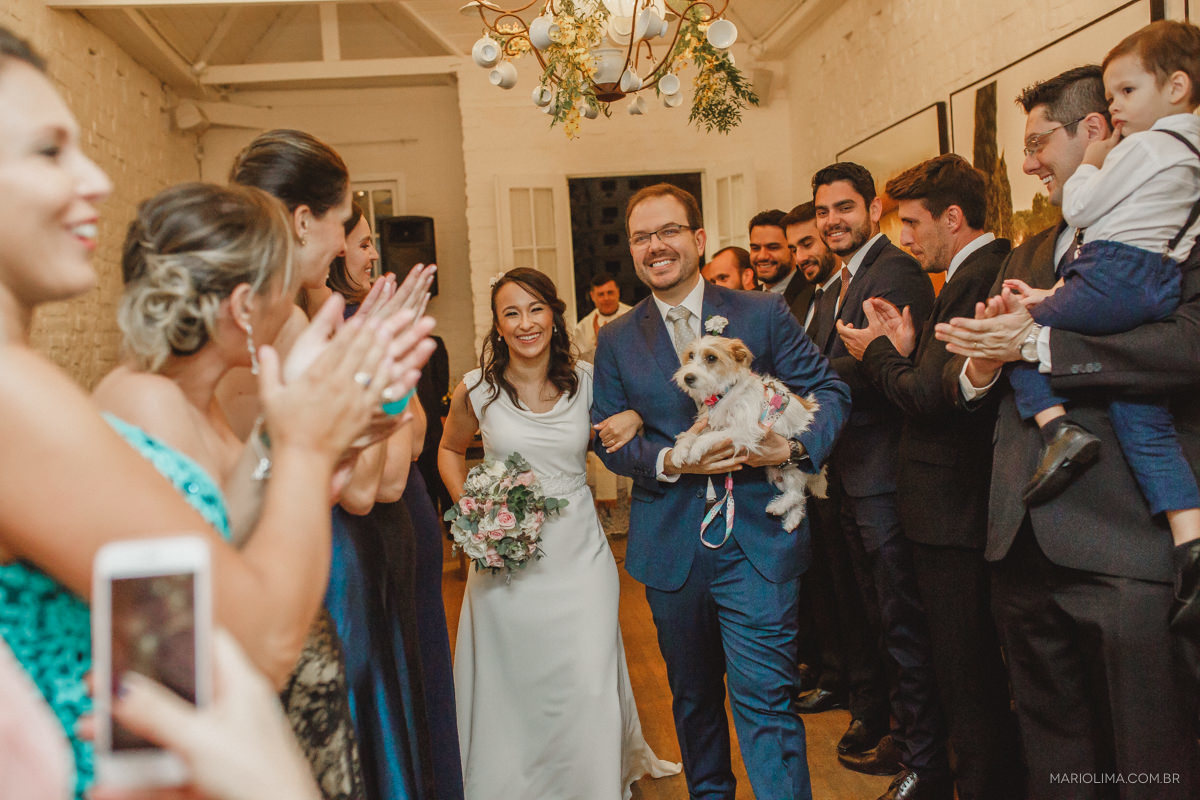  noivos saindo felizes após a cerimonia com a cachorra  no colo