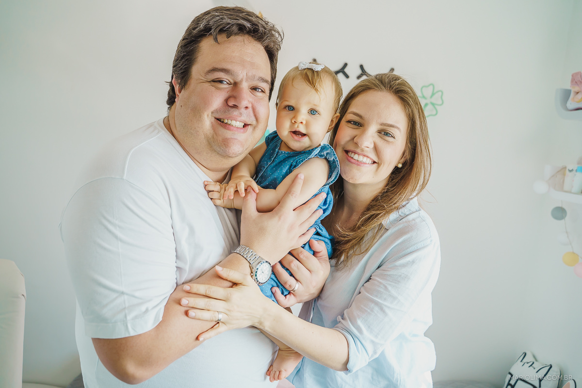 retrato de pai, mãe e bebe sorrindo no quarto da criança