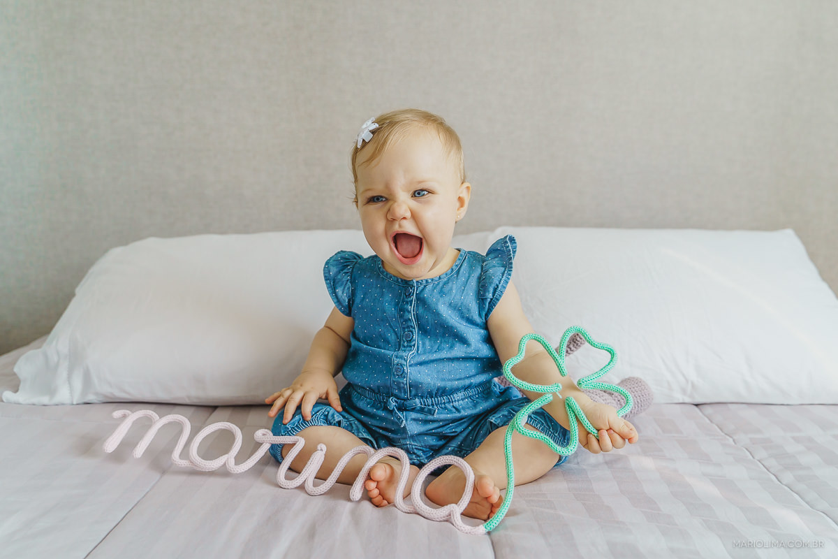 bebe sorrindo com nome em letras marina nas maos 