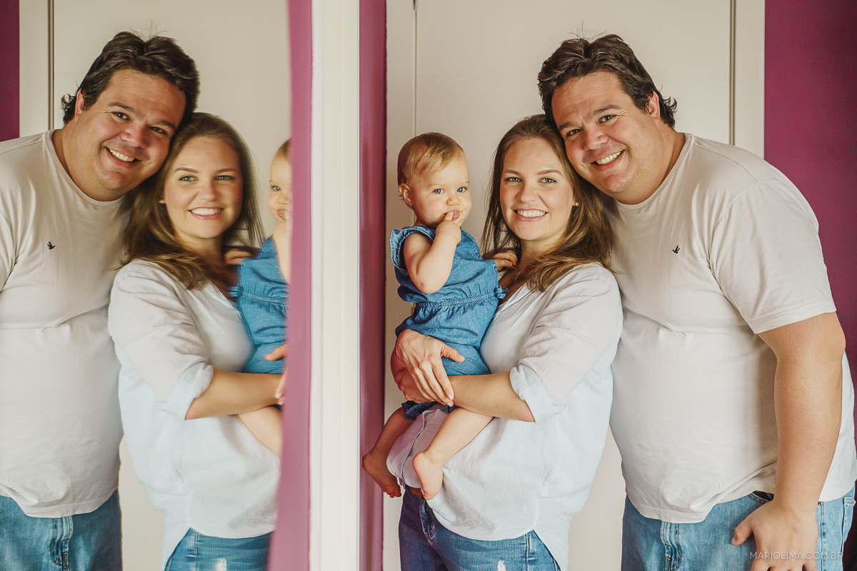 retrato de pai, mãe e bebe sorrindo com reflexo no espelho em casa