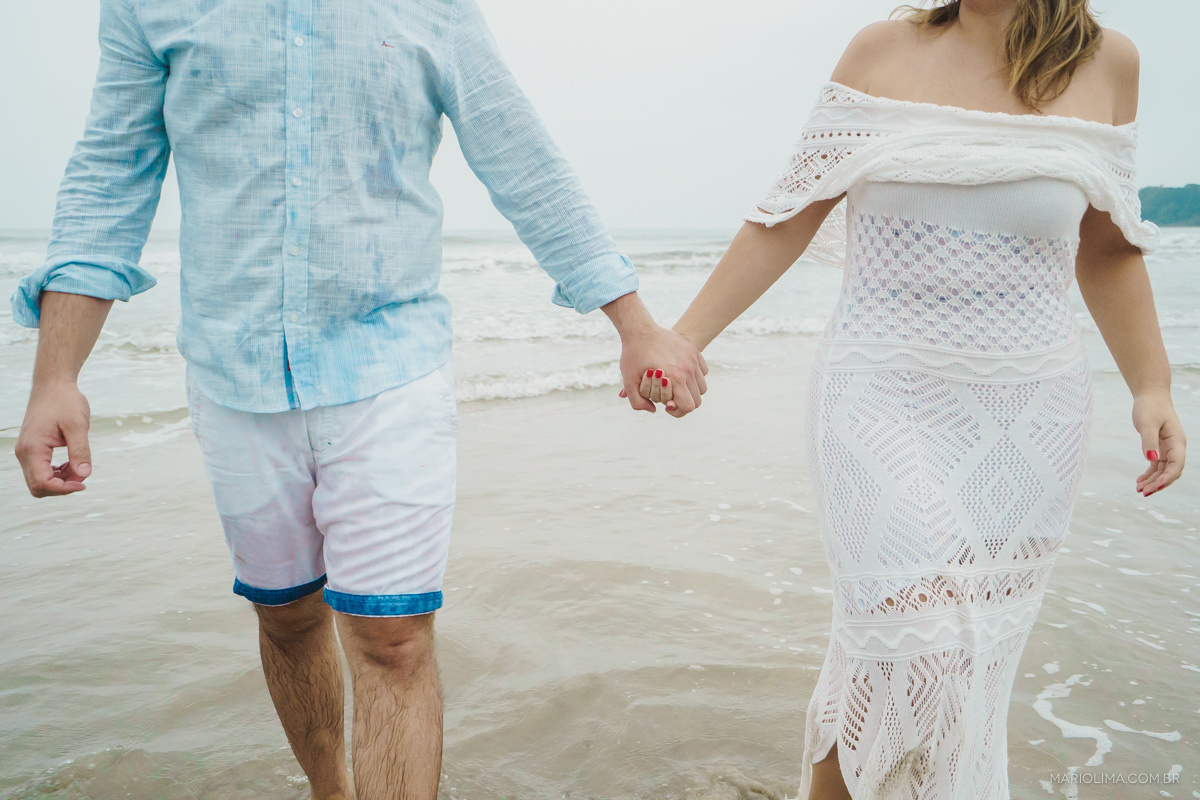casal andando de maos dadas no ensaio pre casamento na praia
