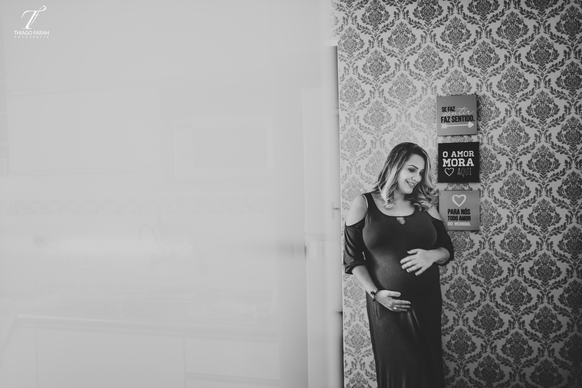 foto preto e branca do ensaio gestante, com quadros na decoração da casa.