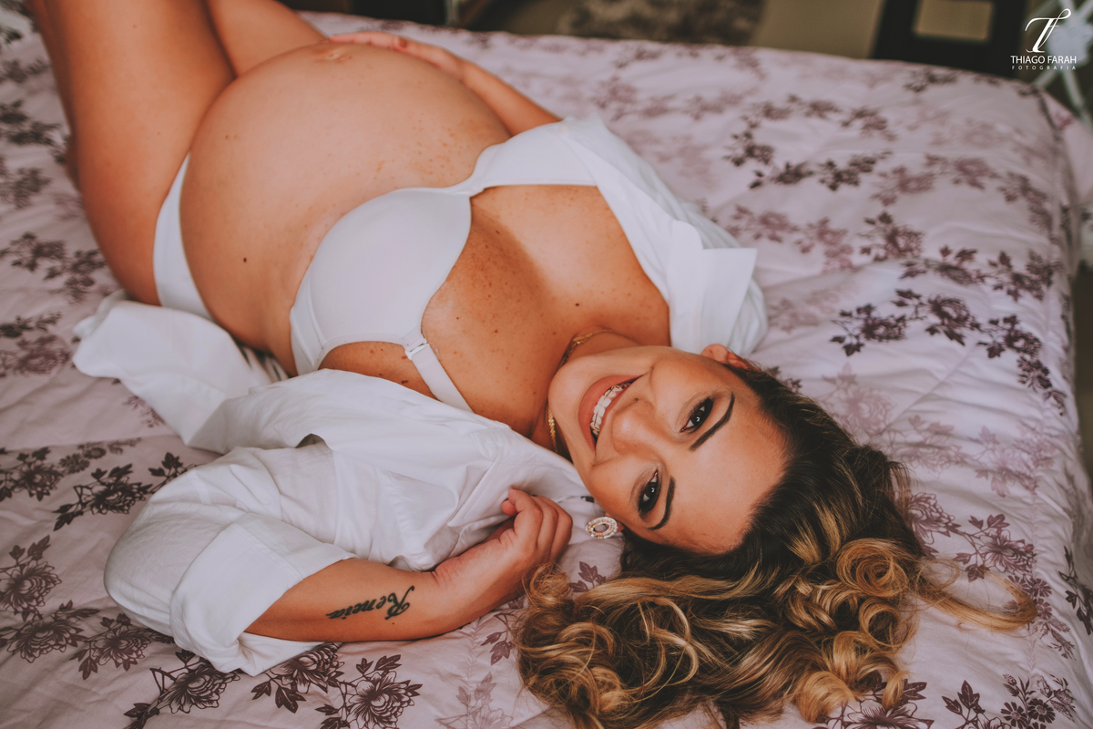 gestante deitada na cama, com colcha lilás, luz natural, ensaio lifestyle