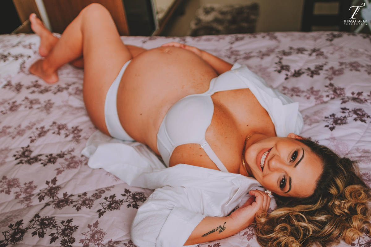gestante deitada na cama, com colcha lilás, luz natural, ensaio lifestyle