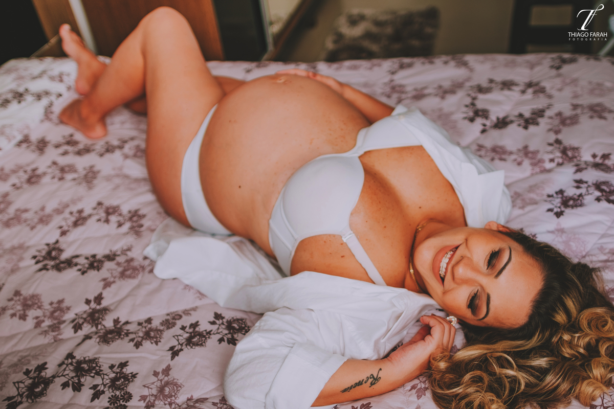 gestante deitada na cama, com colcha lilás, luz natural, ensaio lifestyle