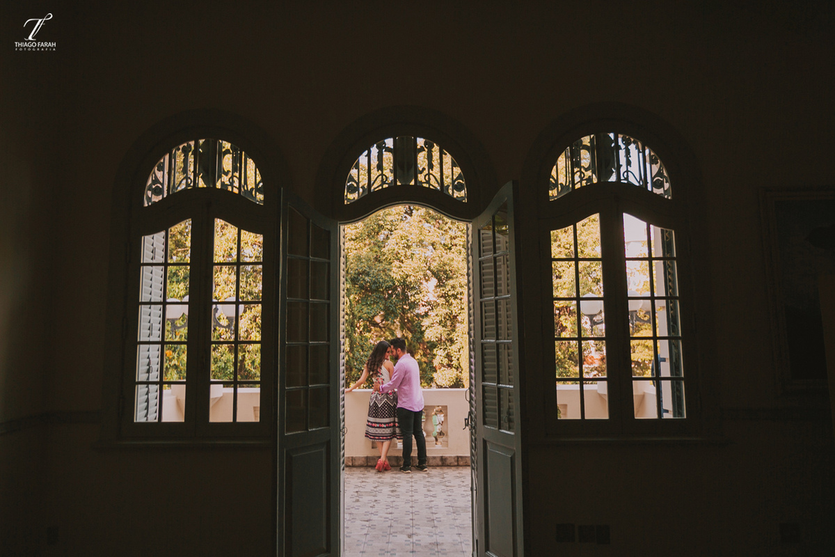 casal juntos abarçados, na sacada, com várias janelas, e arquitetura vitoriana.