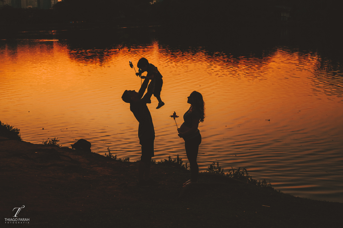 pai levantando no ar filho em ensaio gestante externo ibirapuera, foto contra luz no lago, por do sol, parque ibirapuera