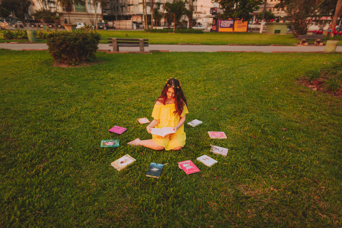 ensaio externo 15 anos em santos, ponta da praia, praça do aquário, gramado, livros, vestido amarelo