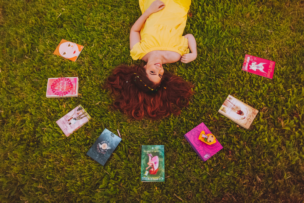 ensaio externo 15 anos em santos, ponta da praia, praça do aquário, gramado, livros, vestido amarelo