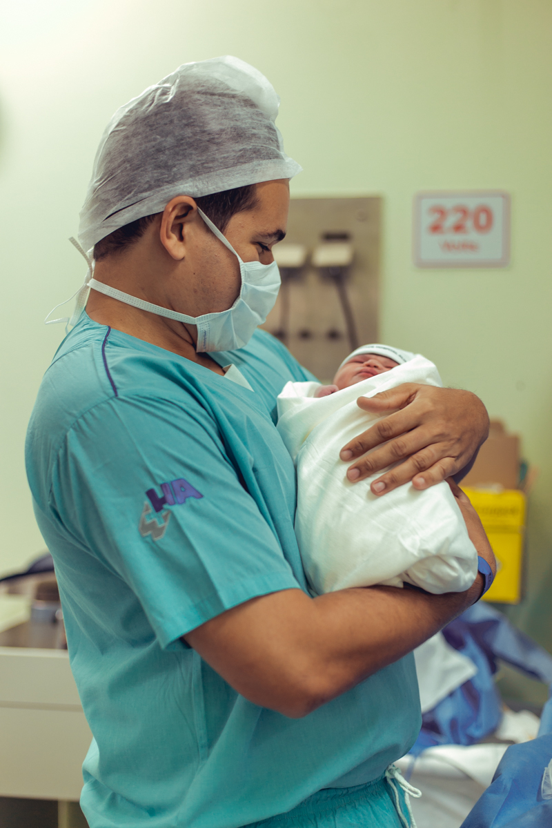 pai feliz carregando sua filha recem nascida no colo