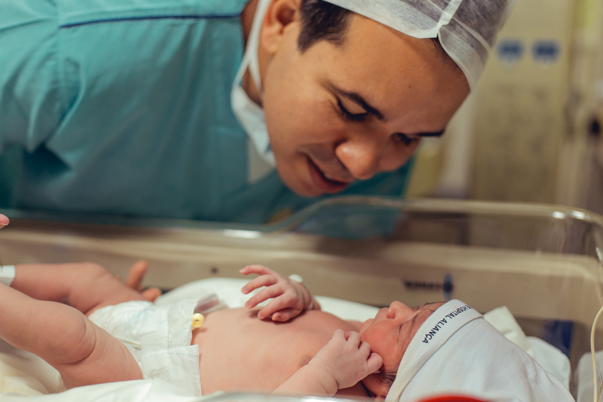 pai admirando a filha recem nascida no berçario de salvador