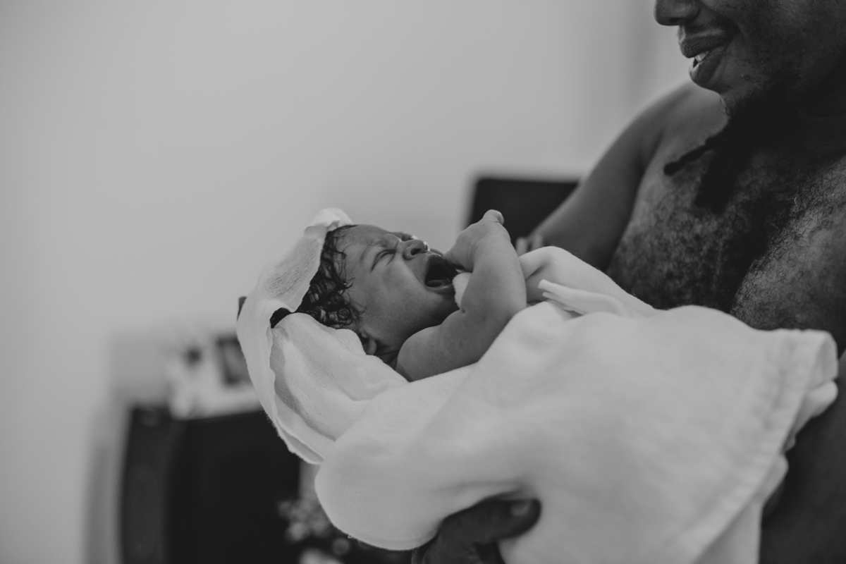 pai carregando filho pela primeira vez apos parto domiciliar humanizado