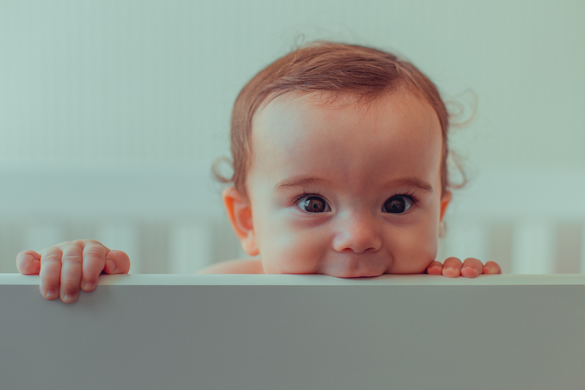 bebe coça dente no berço e faz cara fofa
