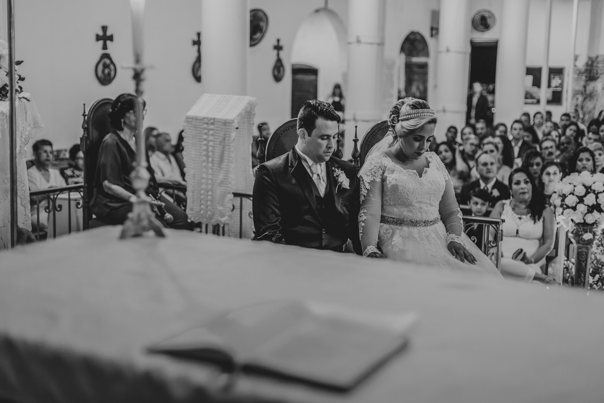 noivos rezando no altar enquanto padre oferta os votos
