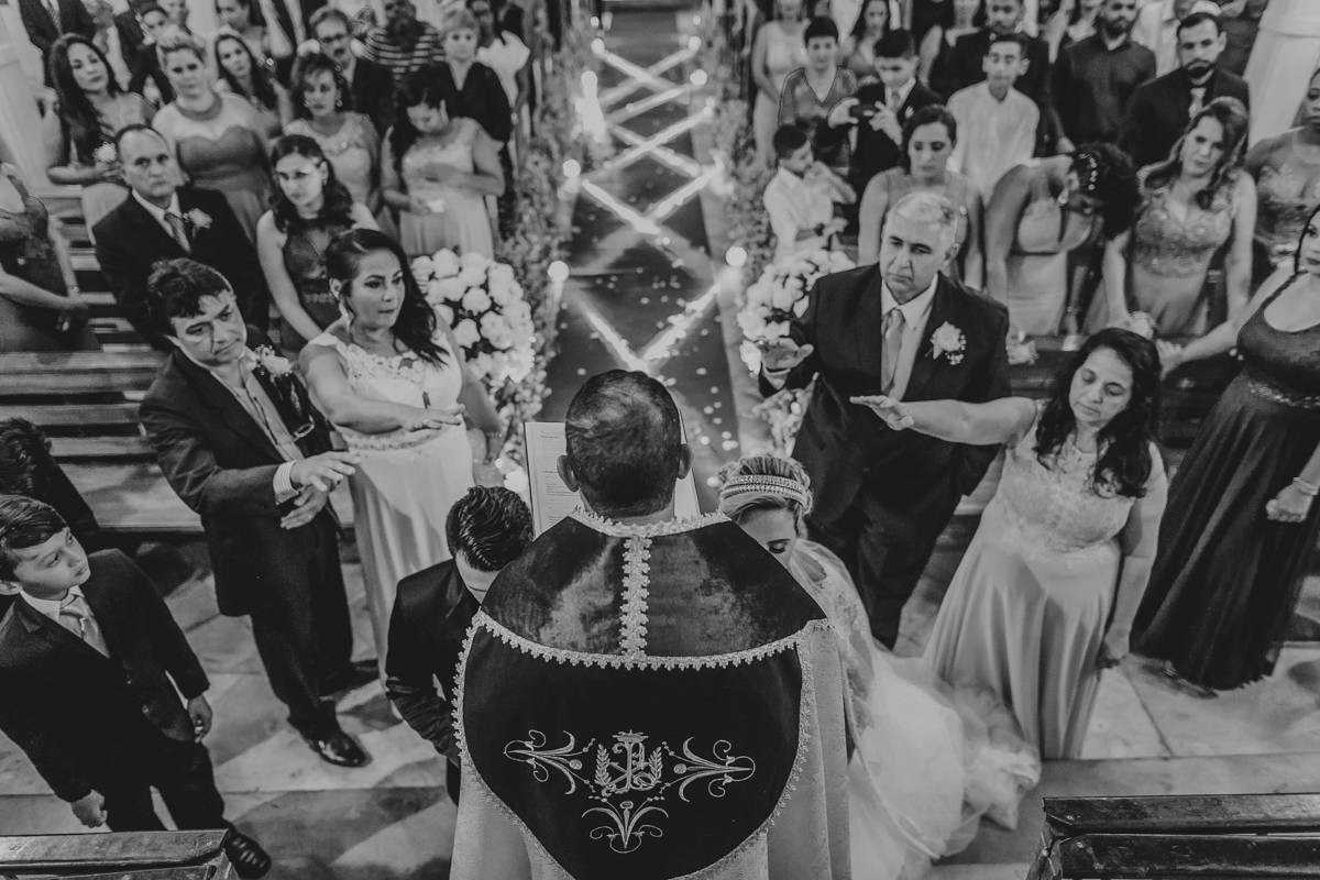 noivos ajoelhados recebendo os votos do padre