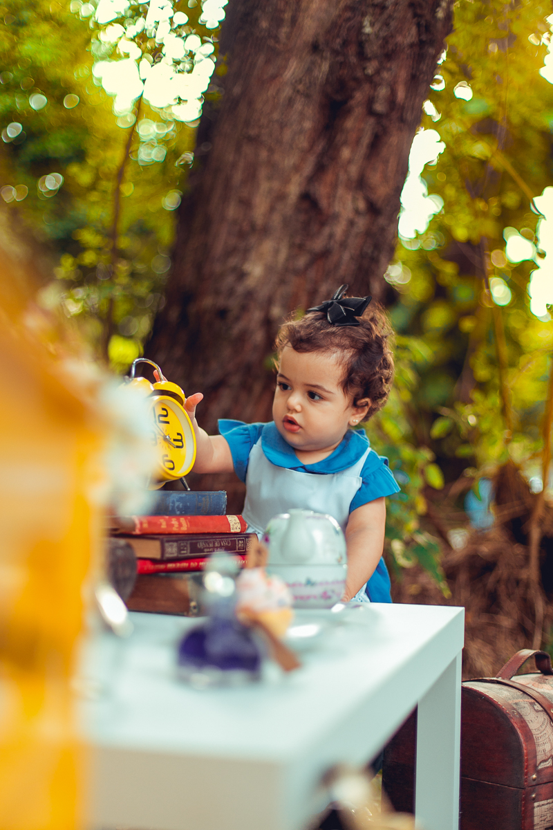 alice brinca com relogio amarelo no ensaio no pais das maravilhas