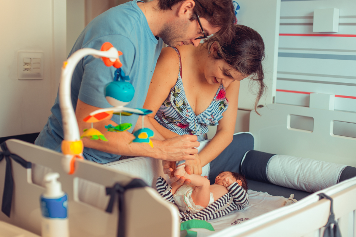 pais trocam fralda do bebe durante sessao de fotos em casa