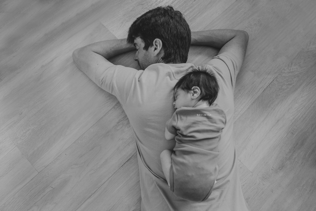 filho recem nascido newborn deitado nas costas do pai