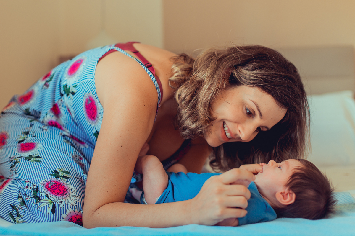 mae e filho recem nascido brincam durante sessao de fotos em ensaio newborn