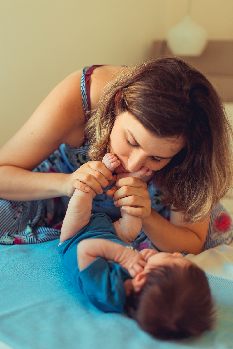 mae beija pé do filho durante sessao newborn lifestyle em salvador