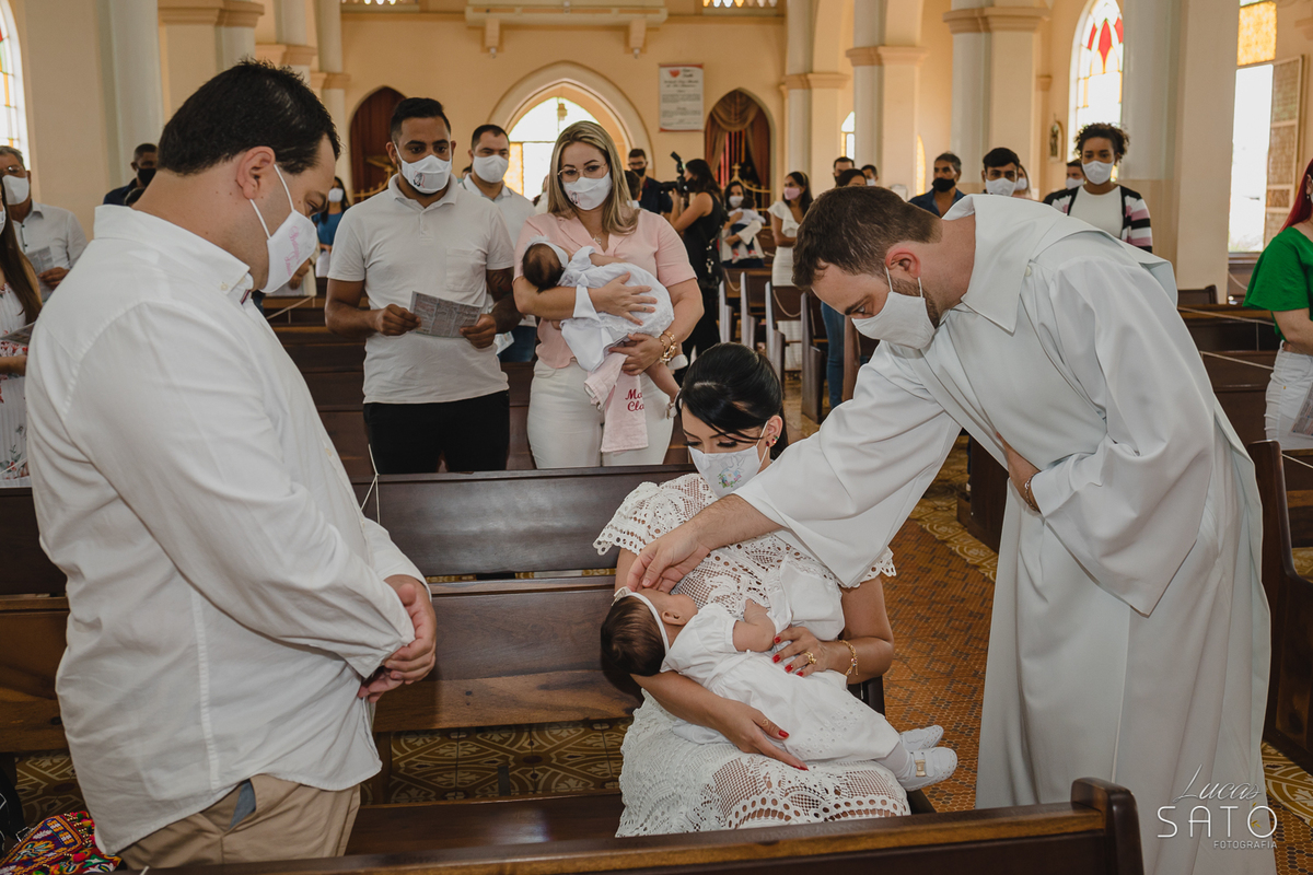Padre passando óleo na testa da criança para o batismo cristão na Igreja Matriz