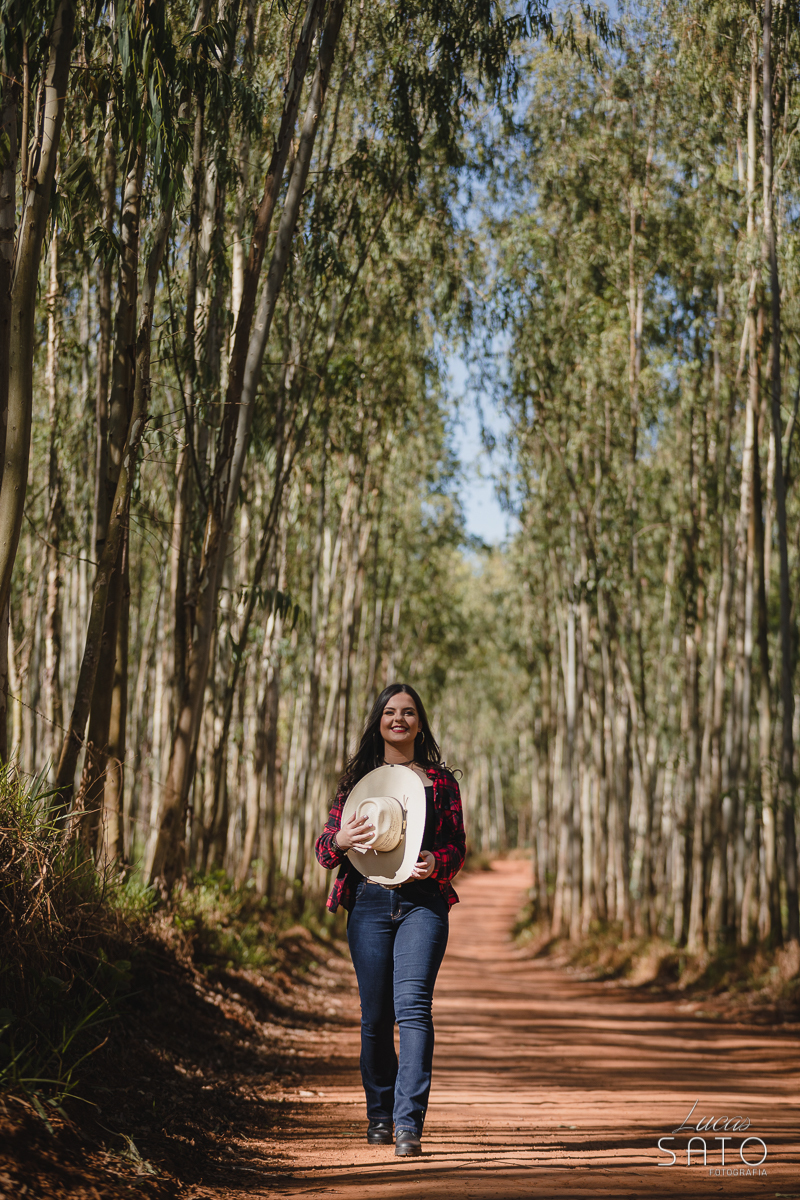 Foto no eucalipto do ensaio de 15 anos da Izabelly realizado em São Gotardo-MG. Book no estilo country com chapéu branco.