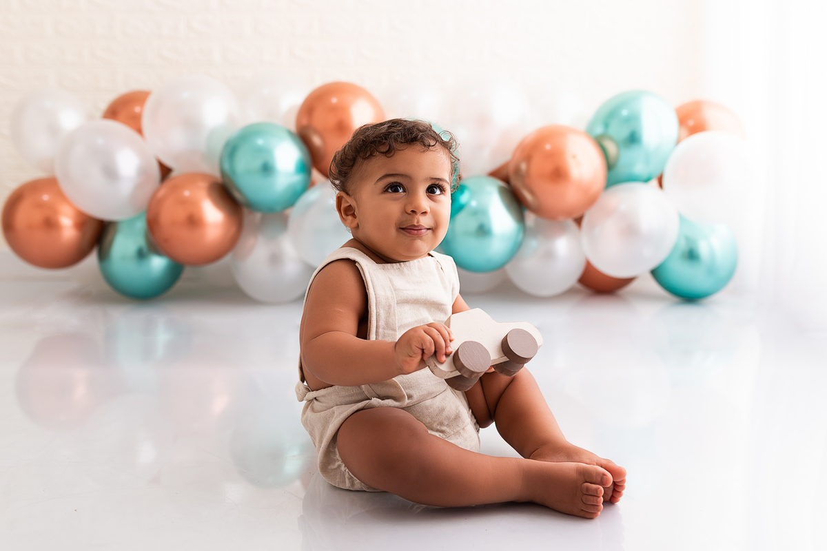 Bebê brincando de carrinho com balões no fundo
