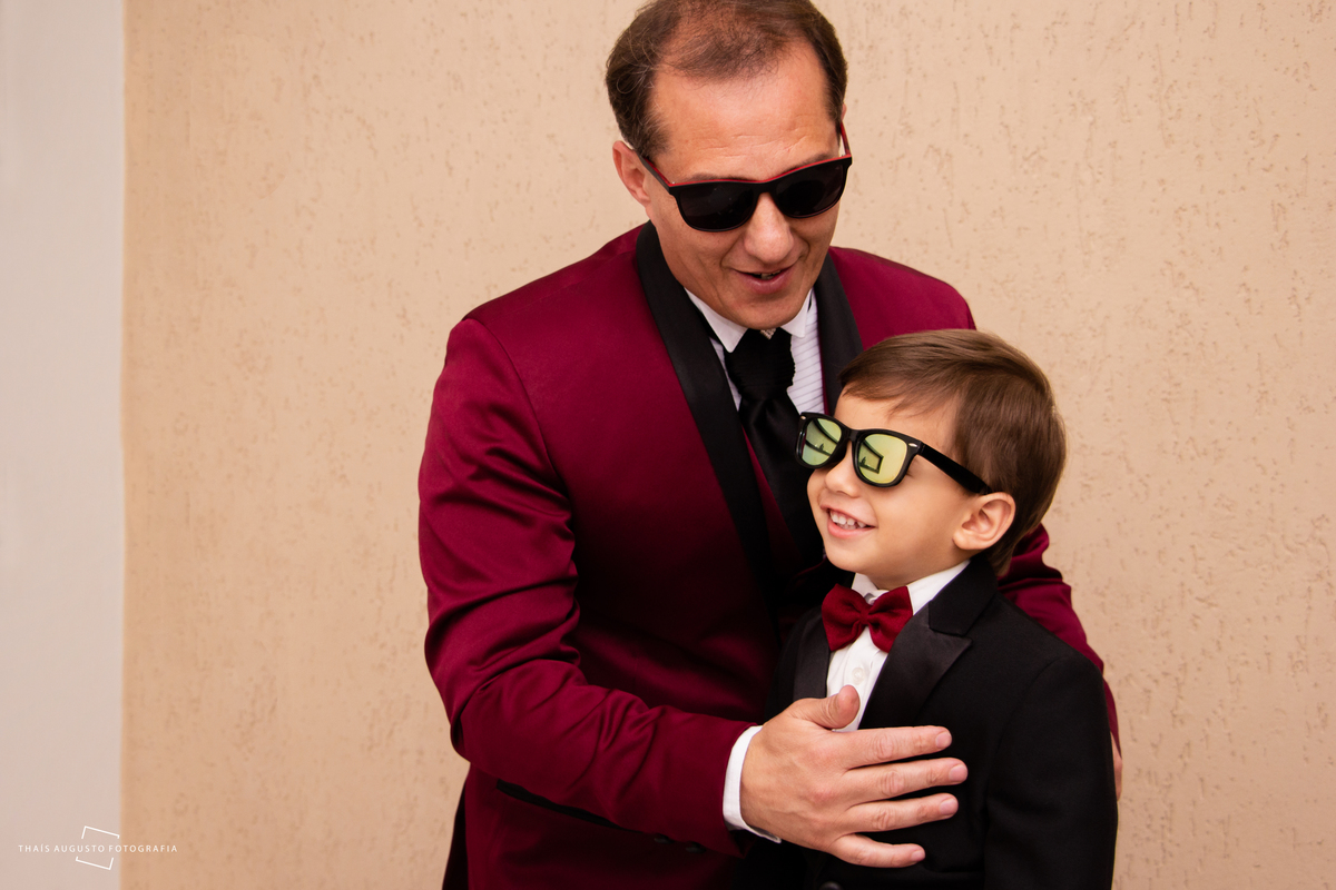 noivo no making of faz foto com filho de oculos de sol e terno marsala, fotógrafa de casamento faz registro e tem momentos especiais
