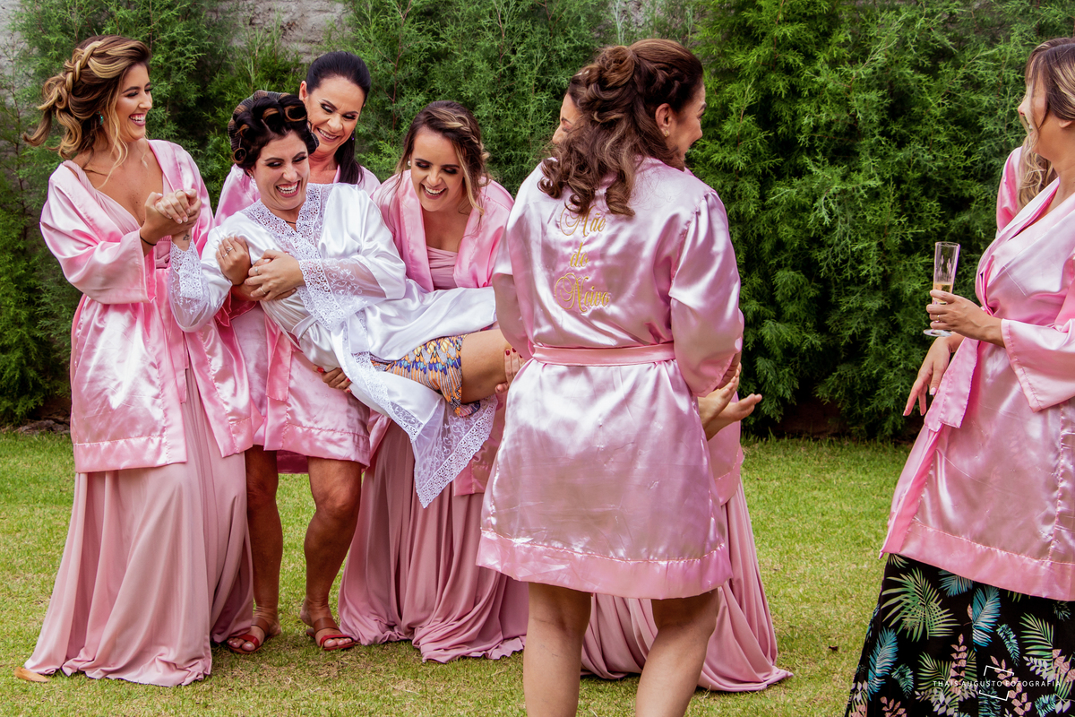madrinhas pegando a noiva no colo no quintal da casa onde foi realizado o making of, a cerimônia do casamento foi na chácara duas meninas em Bauru - SP