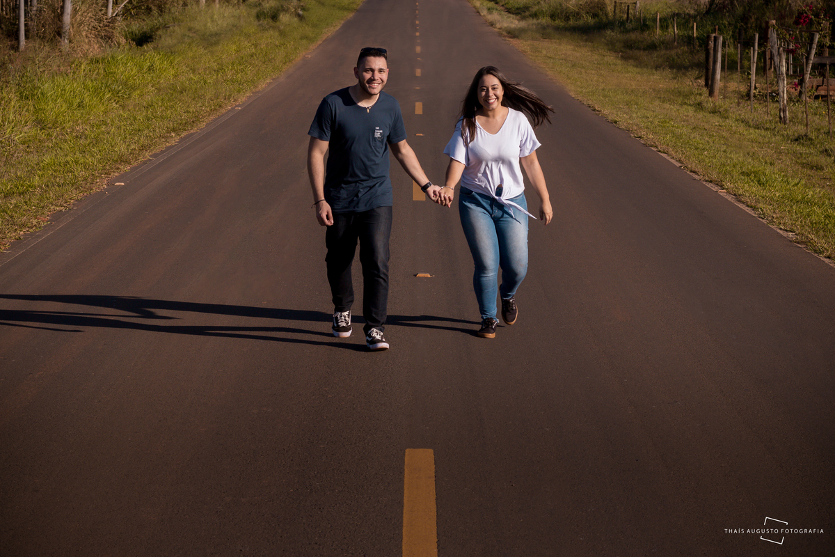 casal se diverte em ensaio fotográfico antes do casamento fotos no meio da estrada ficam divertidas e dinâmicas