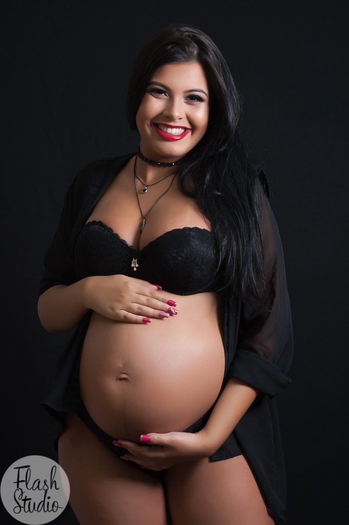 gestante sorrindo e com as maos na barriga, em ensaio fotografico de gestante em estudio, no rio de janeiro - RJ