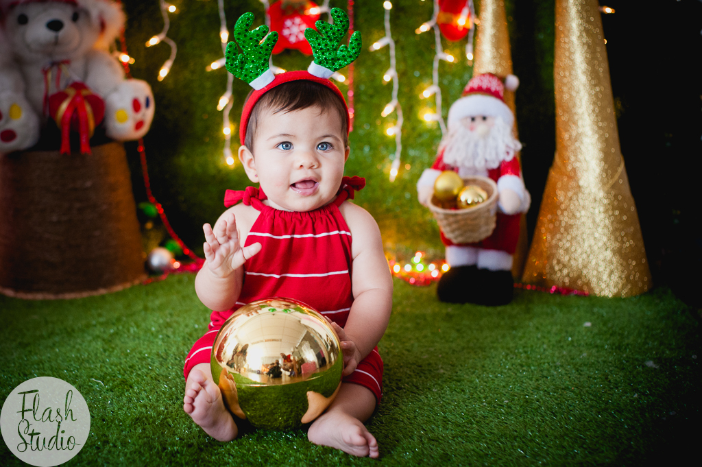 bebe de olhos azuis sorrindo em cenario de natal, em ensaio de natal em bangu no rio de Janeiro