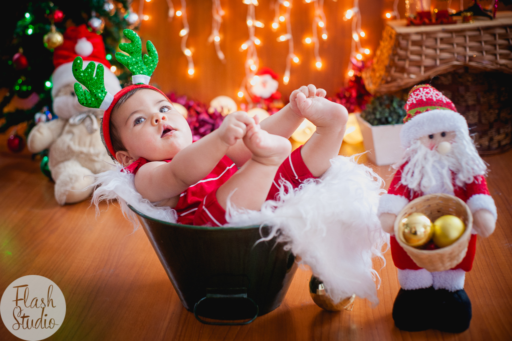 bebe segurando os pezinhos em cenario de natal, em ensaio de natal em bangu no rio de Janeiro