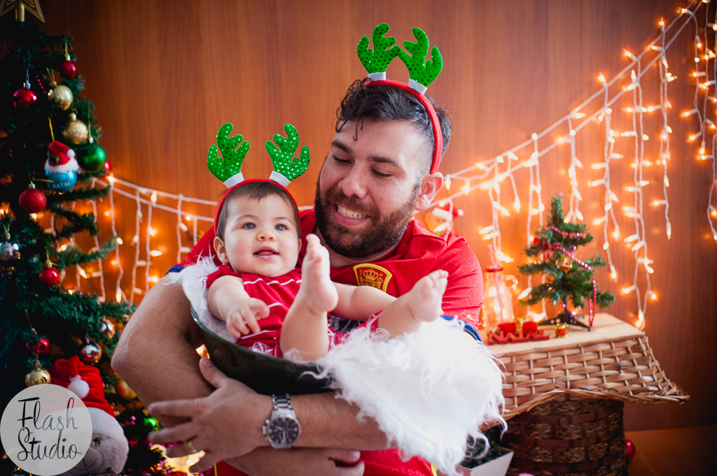 pai sorrir com filha em cenario de natal, em ensaio de natal em bangu no rio de Janeiro