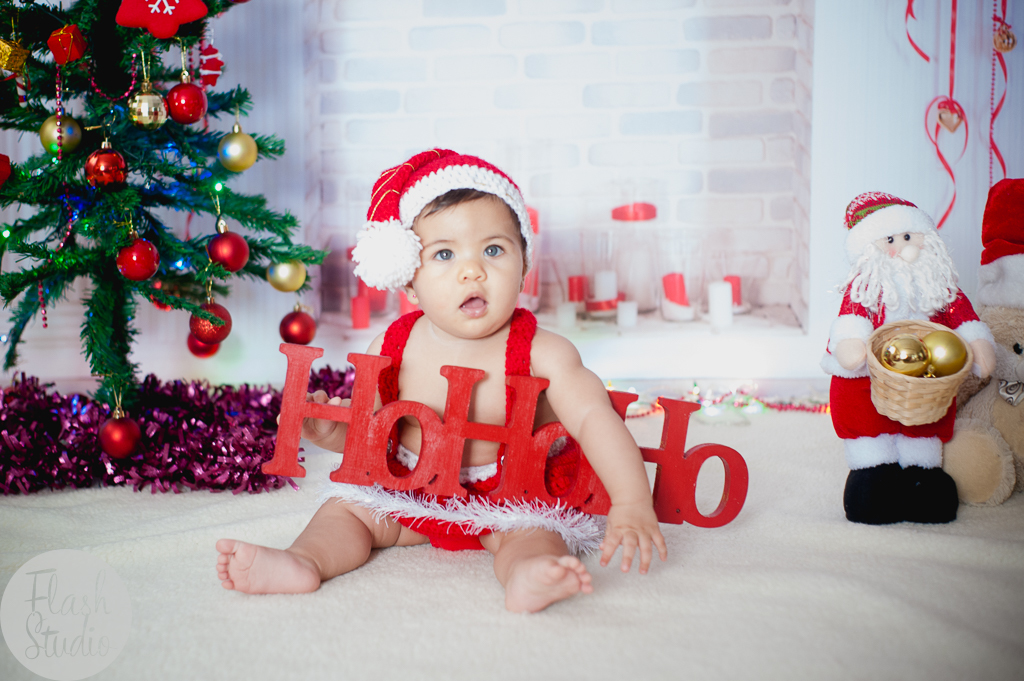 bebe linda com plaquinha de natal em cenario de natal, em ensaio de natal em bangu no rio de Janeiro