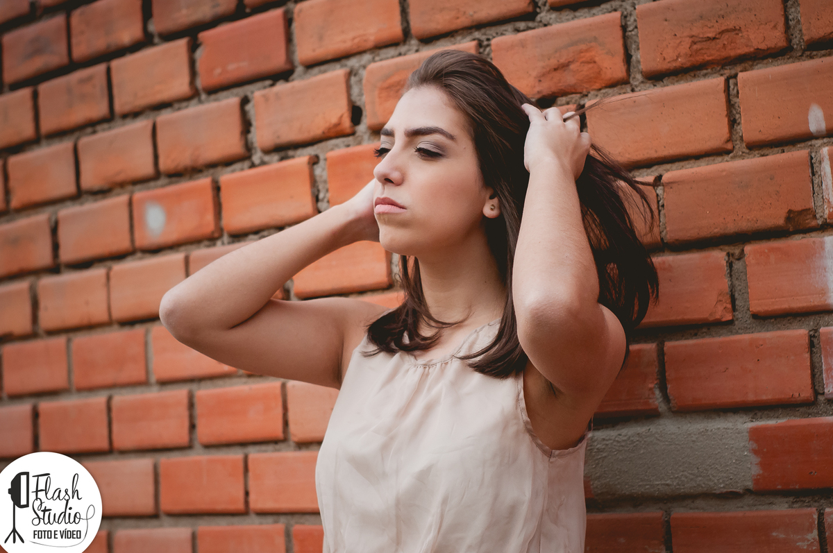 mulher segurando os cabelos em um muro de tijolos um ensaio externo feito no rio de janeiro