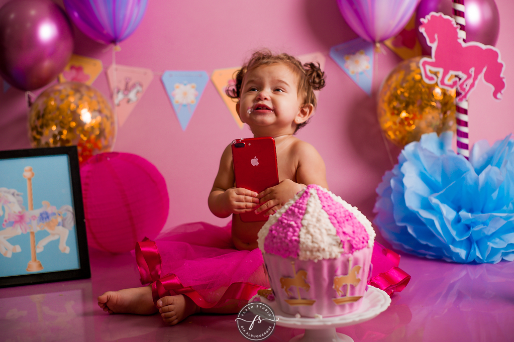 bebe brincando com iphone em cake smash/ smash the cake de carrossel, no rio de janeiro, em bangu