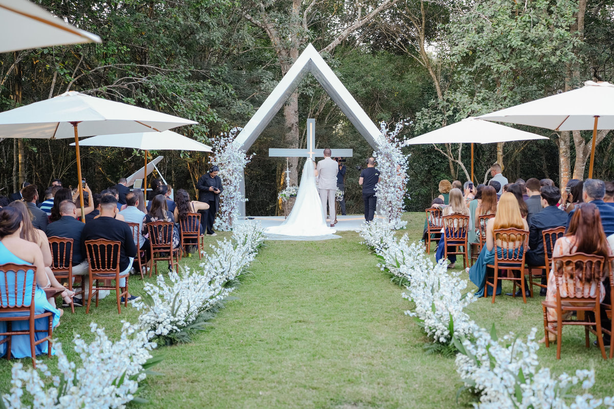 Vista geral da cerimônia de casamento ao ar livre no Sítio Santa Paula, com convidados, decoração floral e altar.