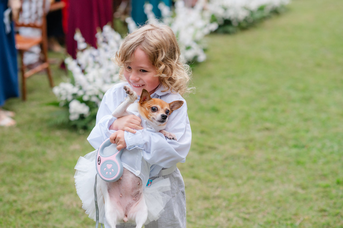 Um momento espontâneo e delicado com uma criança e um cachorrinho durante o casamento de Ana Rute e Juliano.