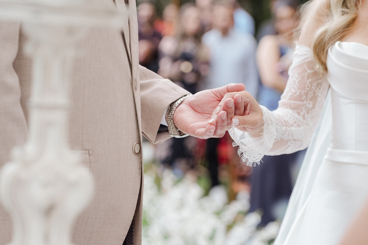 Detalhe das mãos de Ana Rute e Juliano durante a troca de alianças na cerimônia de casamento.