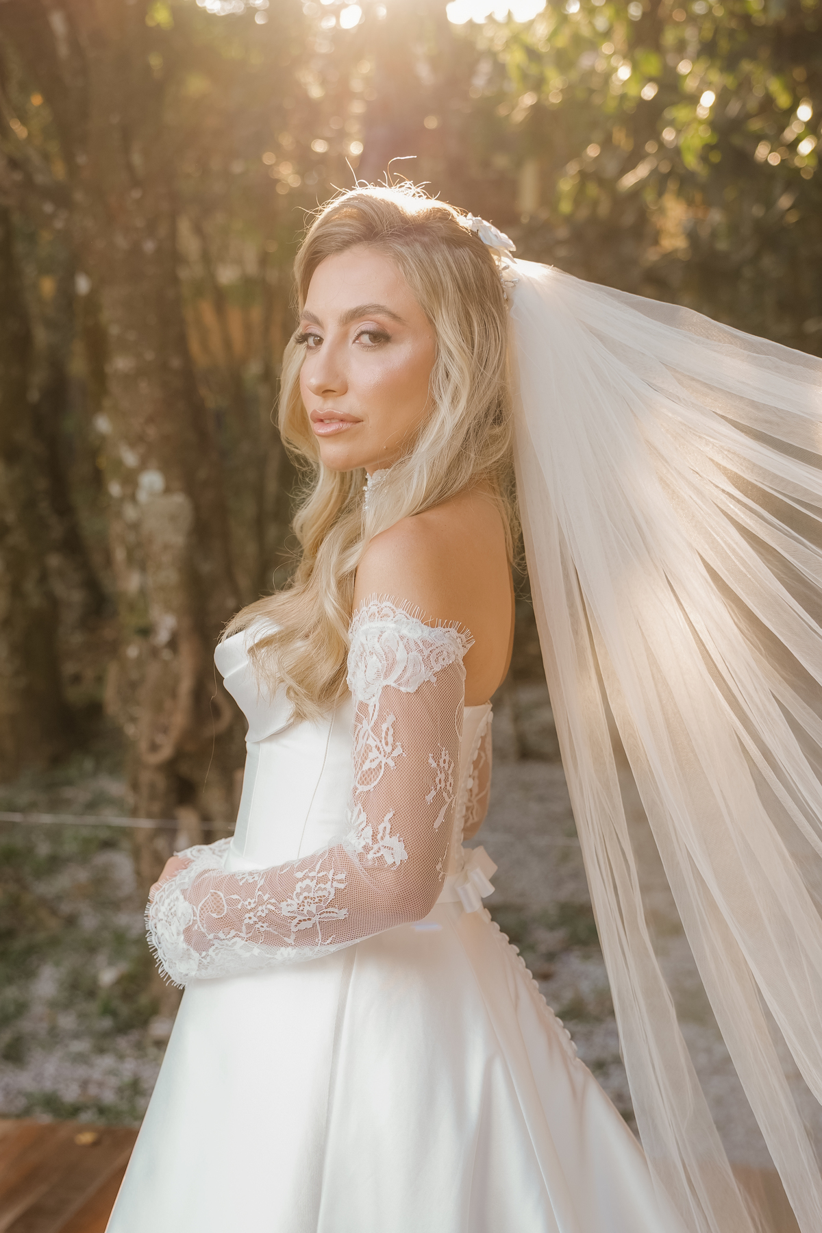 Ana Rute posa com seu vestido de noiva e véu em um retrato delicado ao ar livre no Sítio Santa Paula, em Pouso Alegre.