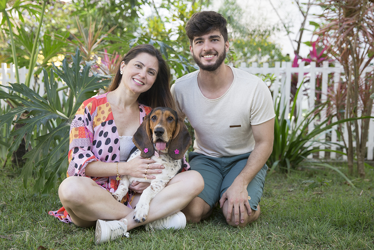 Basset Hound olhando para camera, abraçada com os tutores
