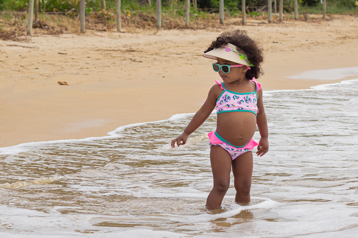 modelo de biquini,  brinca no mar, mostrando seu óculos de sol