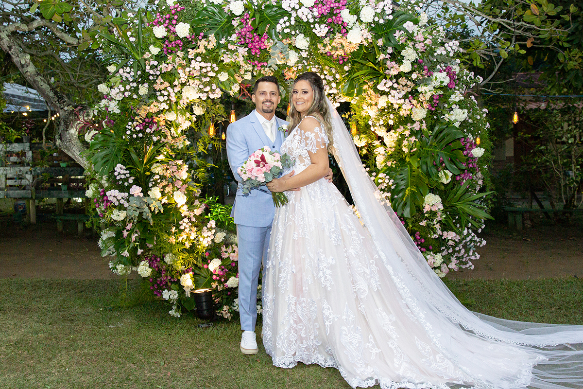 Retrato dos noivos no arco de flores