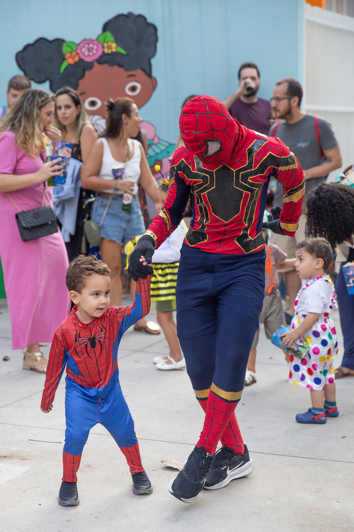 aniversariante comemorando 3 anos vestido de Homem-Aranha durante sua festa no Carretão da Alegria, dançando na calçada