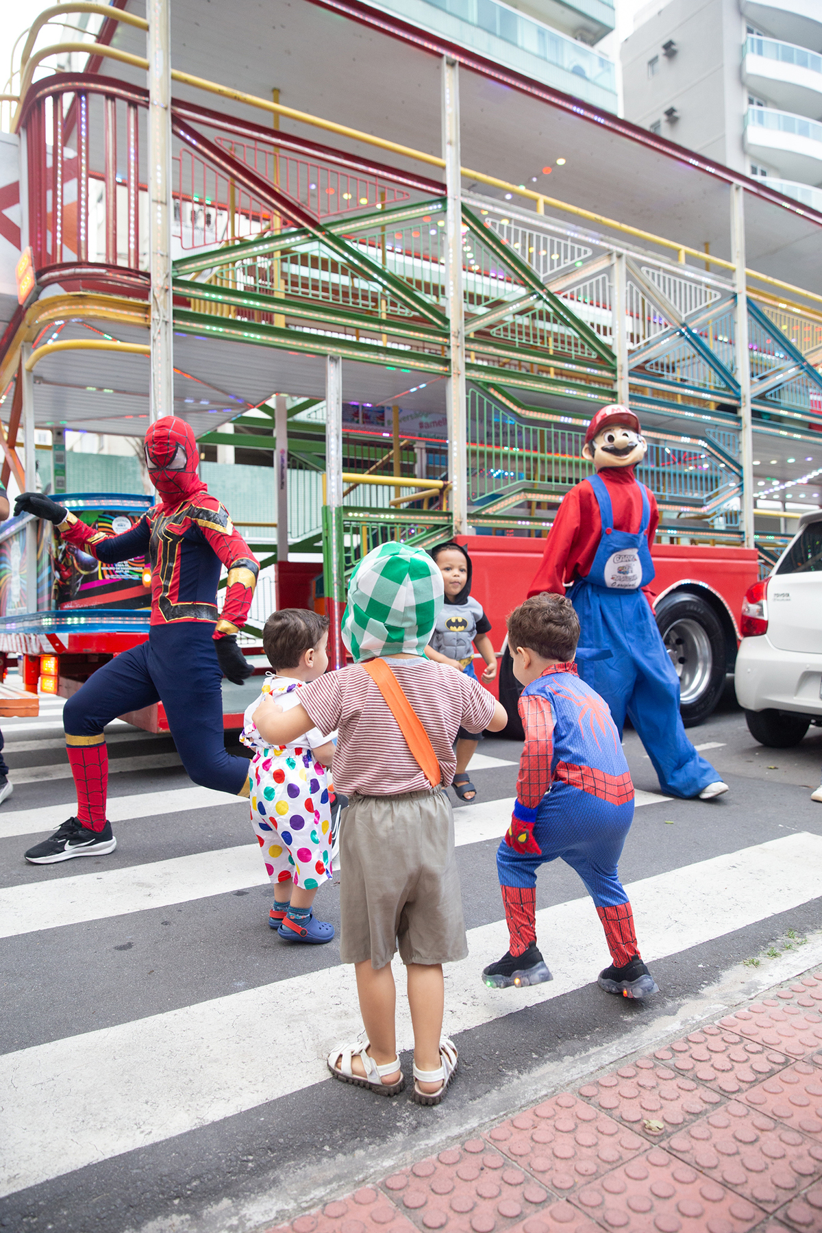 aniversariante comemorando 3 anos vestido de Homem-Aranha durante sua festa no Carretão da Alegria, dançando na calçada